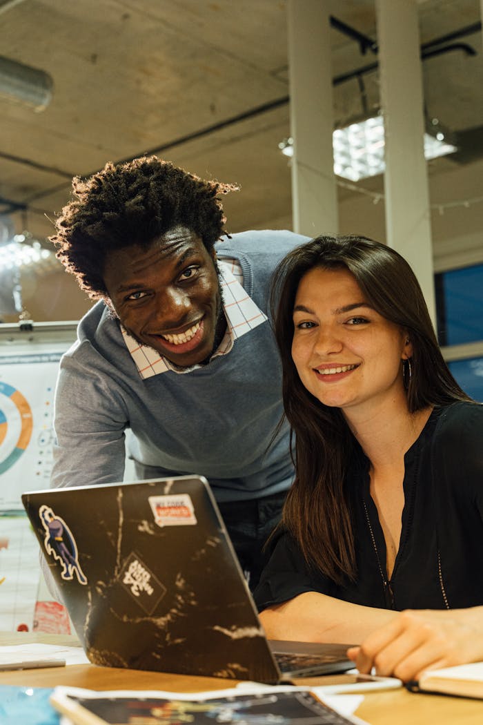 Two diverse coworkers smiling while working together in a modern office.