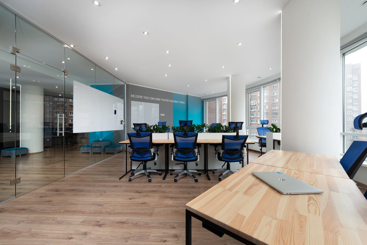 Spacious and contemporary office featuring glass walls, blue chairs, and wooden desks.