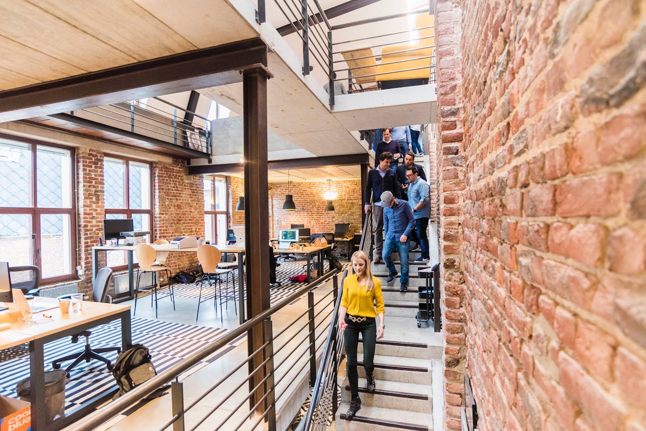Open-concept office with brick walls, multi-level layout, and team members working together.